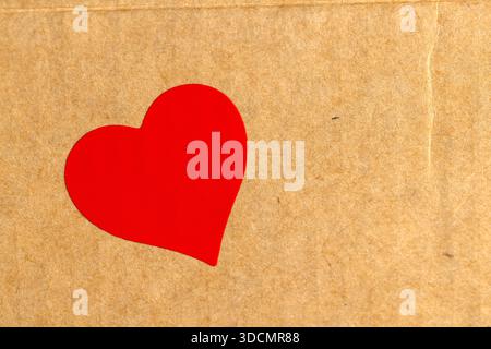 solid yellow cardboard for packaging goods and products with one red plastic hearts glued on , part of the corrugated cardboard packaging board with r Stock Photo