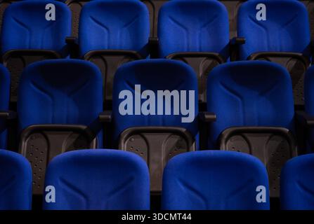 Rows of empty blue chairs providing seating in a modern auditorium, cinema, or conference hall with dark accents Stock Photo