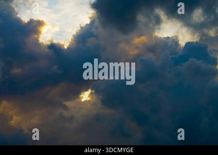 Beautiful evening sky filled with heavy cumulus clouds illuminated by the setting sun Stock Photo