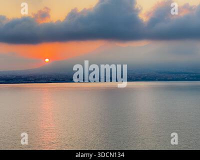 Sunset over the Gulf of Naples with Mount Vesuvius silhouetted beneath dramatic clouds, viewed from Ischia, Campania, Italy. Stock Photo