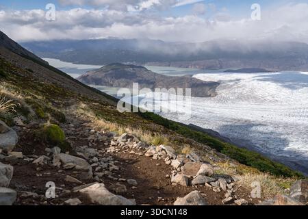 A high-angle view of the Glaciar Grey ice field meeting Lake Grey, seen from the rugged and rocky John Gardner Pass section of the Torres del Paine 'O Stock Photo
