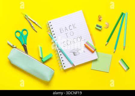 Notebook with text BACK TO SCHOOL, pencil case, stationery and different rubber erasers on yellow background Stock Photo