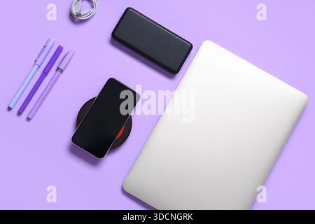 Composition with modern gadgets and pens on lilac background Stock Photo