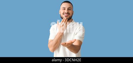 Young man using sign language on blue background Stock Photo