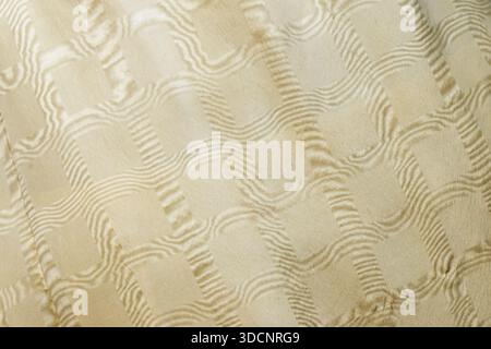 A soft beige fabric featuring a quilted, raised wave pattern. Perfect for textile, decor, and fashion imagery that emphasizes texture and subtle luxur Stock Photo