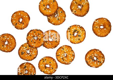 Salted round pretzels with black and white sesame isolated on white. Cracker chips with sea salt isolated on white background. Round shape appetizers. Stock Photo
