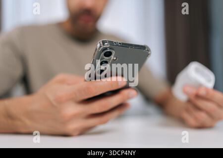 Close-up of man connecting smart plug to home automation system using smartphone app, managing smart devices and establishing internet of things Stock Photo