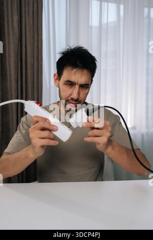 Vertical portrait of focused man examining and connecting smart socket power adapter, introducing new technology for home automation and efficient Stock Photo