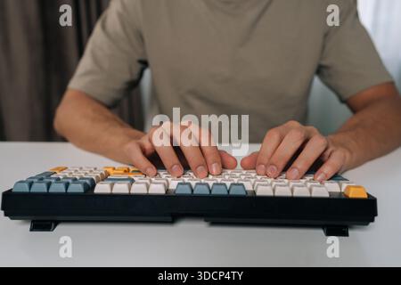 Person hands typing swiftly on stylish wireless mechanical keyboard with colored keycaps, demonstrating efficient digital work, productivity and Stock Photo