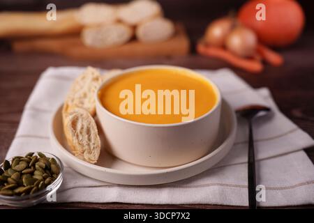 warm autumn scene with creamy pumpkin soup, crusty baguette, and fresh vegetables on a rustic wooden table in soft warm lighting, background, blurred, Stock Photo