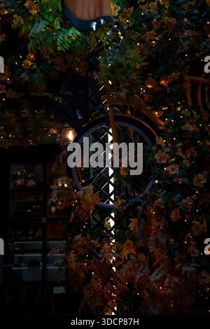 vivid yellow bicycle entwined in lush greenery and warm glow of autumn hues and twinkling lights set against a tranquil night urban ambiance, serene, Stock Photo