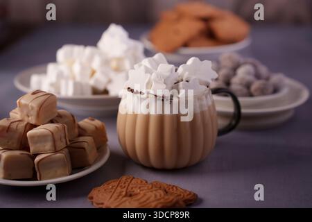 cozy autumn dessert display featuring star-shaped marshmallow hot chocolate and assorted sweets with a warm, inviting atmosphere on a soft purple back Stock Photo