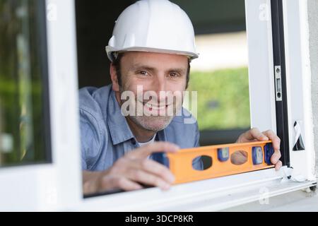 happy builder posing with spirit level at construction site Stock Photo