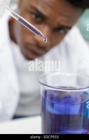 young man scientist using auto-pipette with flask in medical laboratory Stock Photo