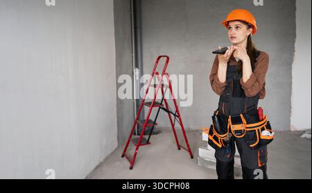 Woman Builder. Female Architect or construction worker talking with voice assistant on mobile phone. Technology, repair, construction and building con Stock Photo