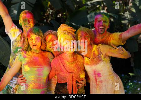 Kathmandu, Nepal – March 10, 2015: Tourists celebrating the Holi festival with raised arms and colorful powder. Stock Photo