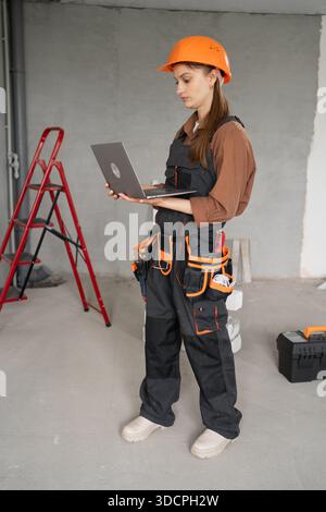 Woman contractor. Female Builder in hard hat and uniform after renovation using computer. Technology, Building and home renovation. copy space Stock Photo