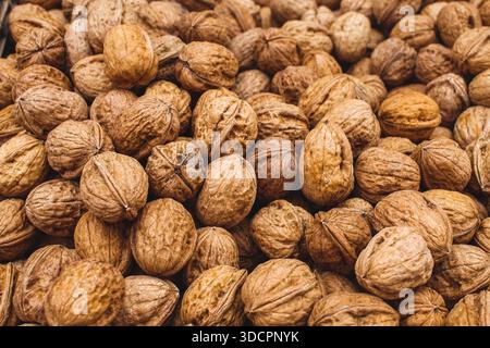 Close-up background of whole walnuts in their shells, showcasing natural texture, organic food concept, and healthy nutrition Stock Photo