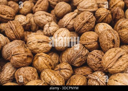Close-up background of whole walnuts in their shells, showcasing natural texture, organic food concept, and healthy nutrition Stock Photo