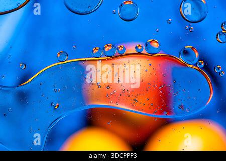 Macro abstract of oil bubbles on blue liquid with warm orange highlights. Stock Photo