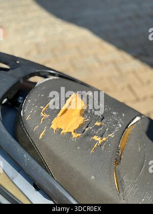 Ripped motorcycle seat with visible damage and exposed foam, suitable for background use. Mobile photo Stock Photo