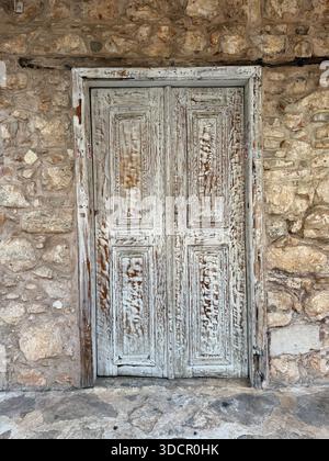 Weathered wooden door on ancient stone wall showcasing rustic textures and historical background. Mobile photo Stock Photo
