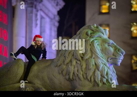 Child with Santa hat playing on stone lion. Stock Photo
