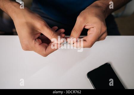 Close-up of technician hands replacing sim card in smartphone, providing efficient customer support and resolving connectivity issues. Stock Photo