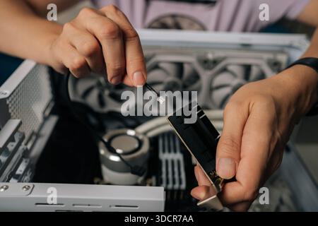 Skilled technician male hands inserting wireless network module inside computer tower, highlighting professional computer maintenance and hardware Stock Photo