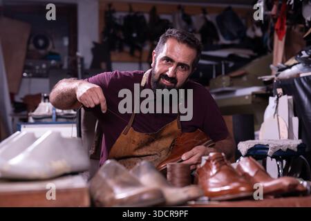 Cobbler at work in a leather workshop crafting brown dress shoes with focused skill and craft Stock Photo