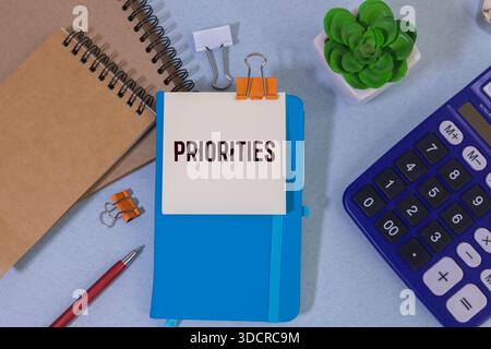 A sheet of kraft paper torn from a notebook lies on the table. Text on PRIORITIES sheet. Colored pens and a pencil. Stock Photo