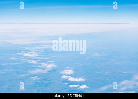 Aerial view showing a distinct, clear horizon line separating deep blue upper atmosphere from lower layer of scattered white cumulus clouds. Wide expa Stock Photo