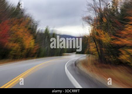Winding country road through forest, autumn leaves, Indian summer, dark rain clouds, smudge effect, blur, symbolic photo, speed, Kancamagus Highway, W Stock Photo