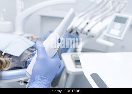 Gloved hand holds intraoral 3D scanner for digital impression and CAD CAM workflow in modern dental office Stock Photo