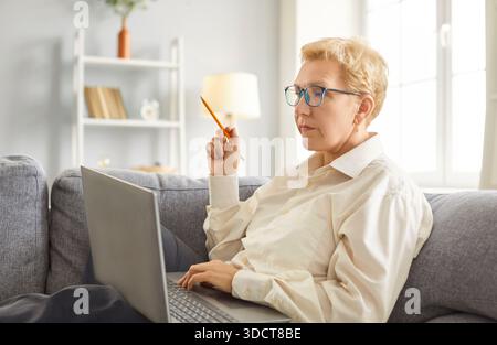 Focused senior woman at home, elder business lady working using laptop watching learning webinar Stock Photo