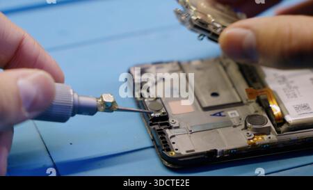 Hands using screwdriver to fix a disassembled mobile phone. Stock Photo