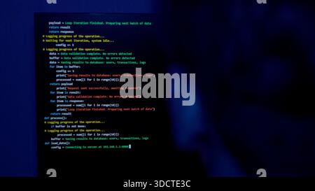 Programmer working on laptop with code on the screen in the dark Stock Photo