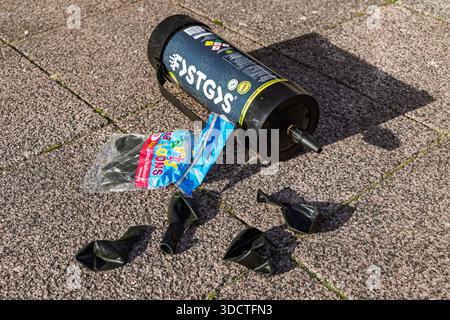 Discarded canister of laughing gas and a package of balloons left on the street, highlighting the issue of nitrous oxide litter. Stock Photo