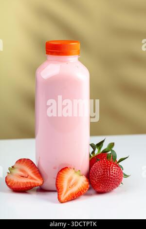 Strawberry milkshake smoothie in eco disposable jar and fresh berries. Smoothie, vitamin drink, or yogurt in plastic bottle on a colorful background. Stock Photo