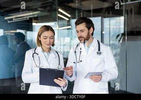Medical professionals collaborating in a modern clinic, reviewing patient data on a digital tablet and clipboard while discussing diagnosis, treatment options and care plans Stock Photo
