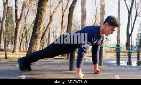 Young man doing push-ups on a ground in autumn park Stock Photo