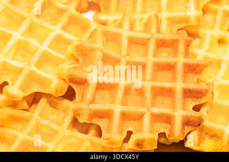Waffles overlap in crisp, appetizing stack, their grid pattern catching warm light. Texture and color suggest freshly made perfect for cozy breakfast Stock Photo
