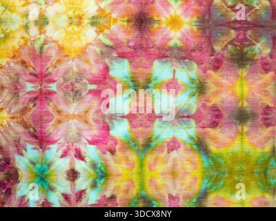 Colorful handcrafted ice-dyed cotton fabric with repeating pattern in pink, light turquoise, gold, and green. Stock Photo