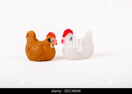Two handmade marzipan chicken figurines, one white and one brown, isolated on white background. Stock Photo
