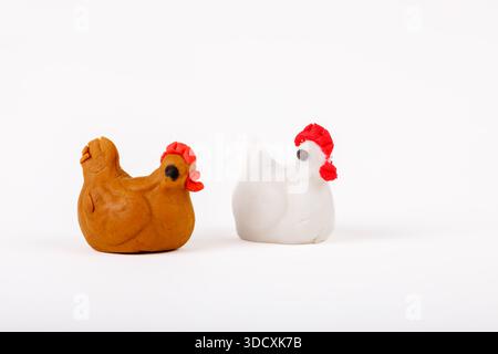 Two handmade marzipan chicken figurines, one white and one brown, isolated on white background. Stock Photo