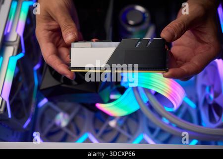 Upgrading computer with RGB lighting, Close up of hardware components during upgrade, Detailed view of installing RAM module into gaming computer with Stock Photo