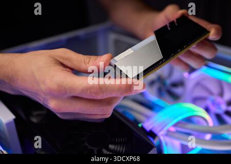 Upgrading computer with RGB lighting, Close up of hardware components during upgrade, Detailed view of installing RAM module into gaming computer with Stock Photo