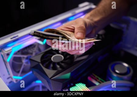 Hidden cash stored in computer memory modules, Covert operation involving cash hideaway inside memory hardware amid colorful RGB illumination and Stock Photo