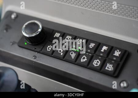 Heavy equipment operator control panel with labeled buttons, rotary dial, and green indicator lights inside modern excavator cabin Stock Photo
