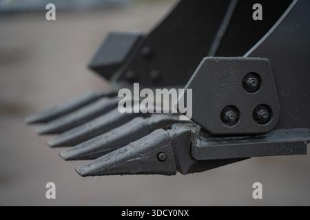 Construction excavator digging attachment featuring steel bucket teeth and connector plate, focused on earthmoving machinery engineering and durabilit Stock Photo
